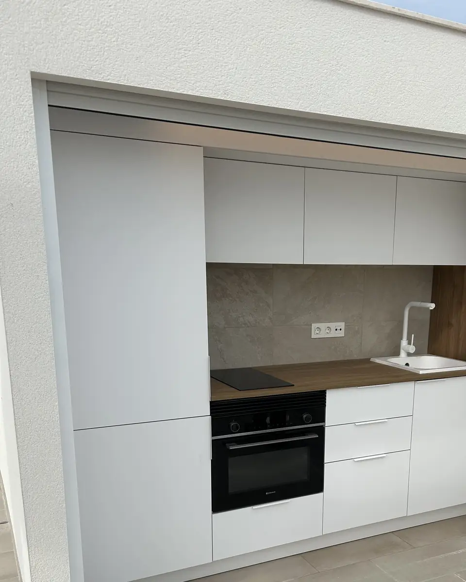 De buitenkeuken op het dakterras, met kookplaat, oven en spoelbak
