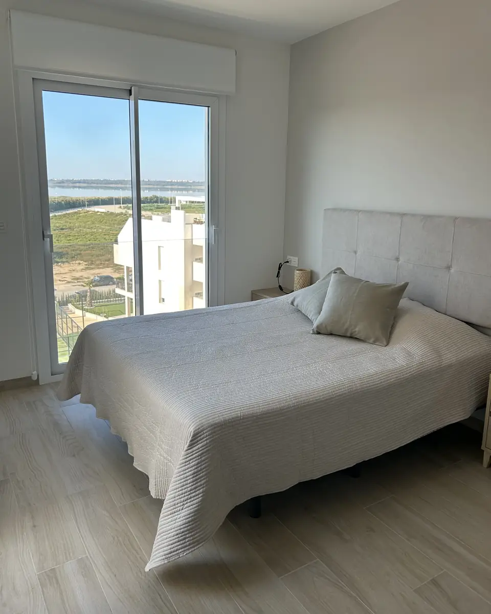 Slaapkamer met een tweepersoonsbed en een schuifdeur met uitzicht op het zoutmeer